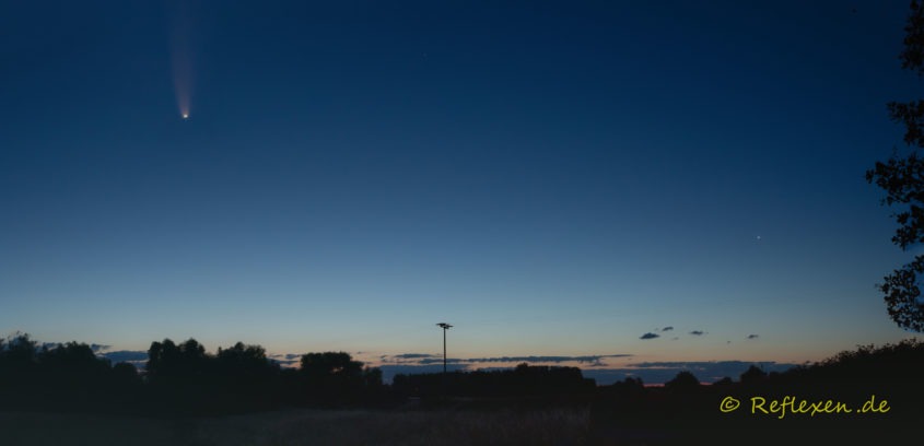 Panorama einer morgendlichen Landschaft mit dem Kometen NeoWise am Nachthimmel.